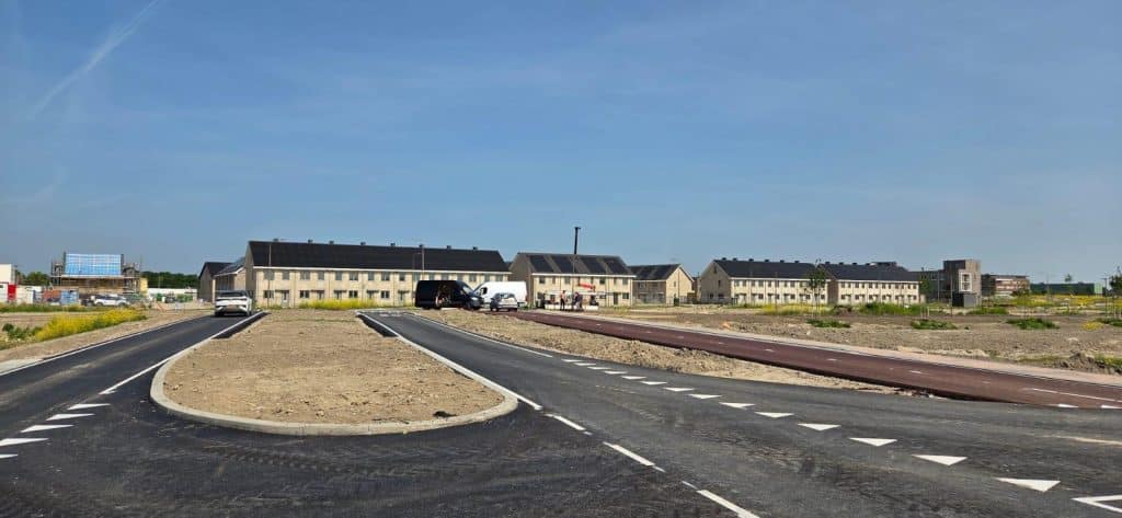 een weg met aan de rechterkant een fietspad en uitzicht op woningen
