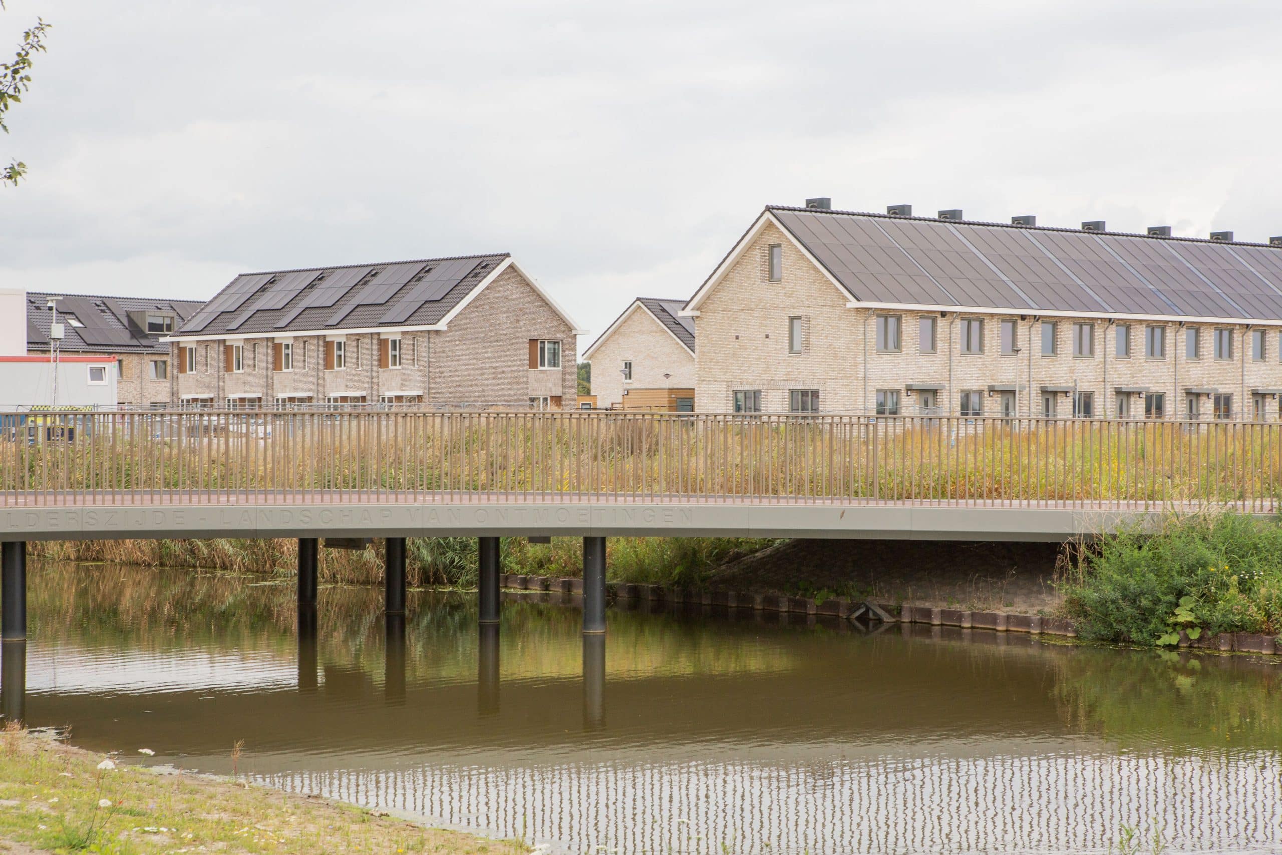 water met een brug en op de achtergrond woningen